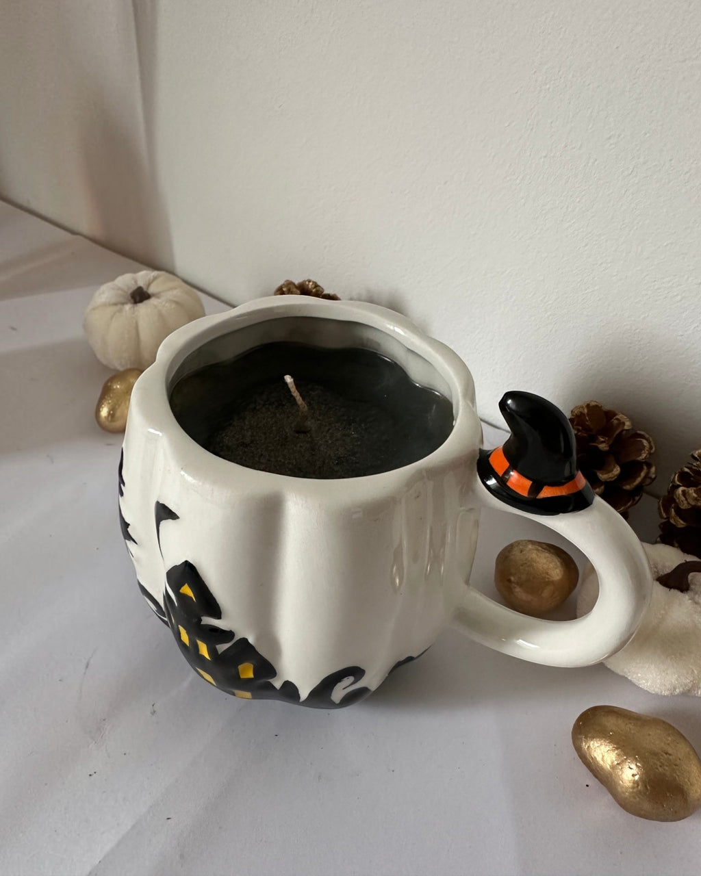 Κοντινή λήψη κεριού Spicy Pumpkin με μαύρο κερί σε λευκή κούπα Halloween