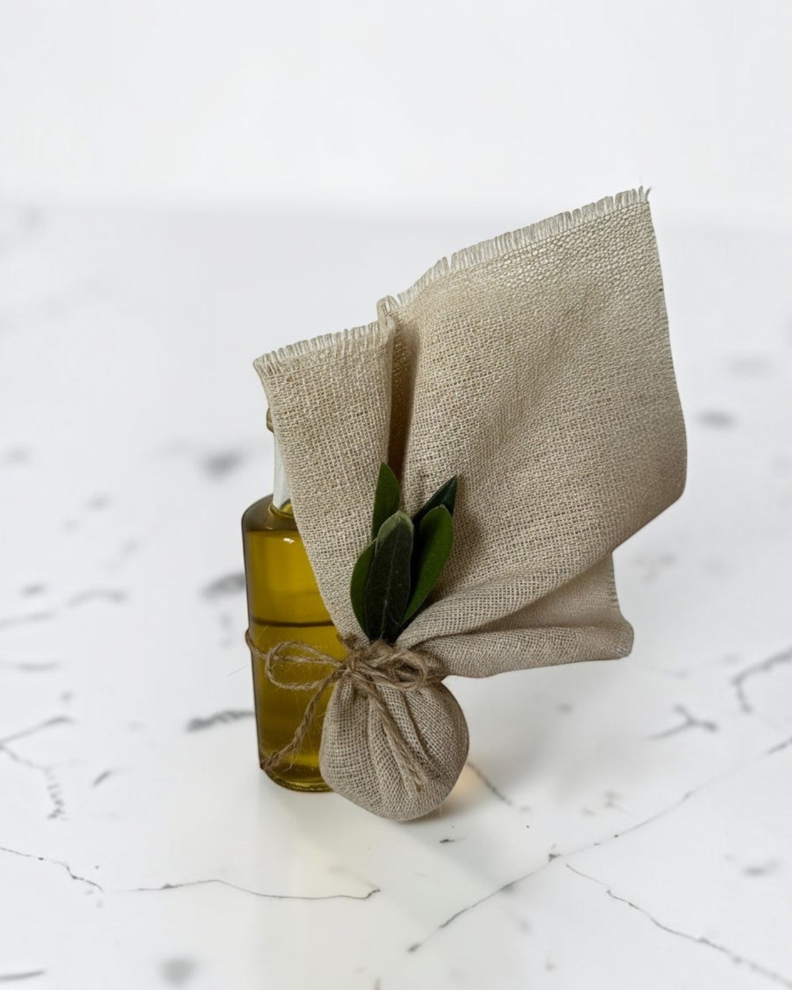 ELAIOPHOS miniature olive oil bottle with burlap accent and twine, featuring green olive leaves.