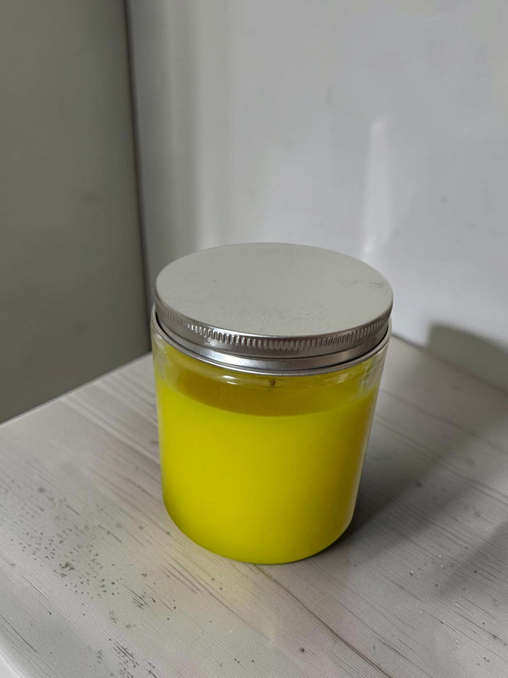 ELAIOPHOS vibrant yellow scented candle in a clear glass jar with a silver lid, perfect for home decor and ambiance.
