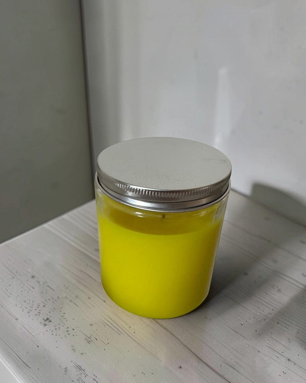 ELAIOPHOS vibrant yellow scented candle in a clear glass jar with a silver lid, perfect for home decor and ambiance.