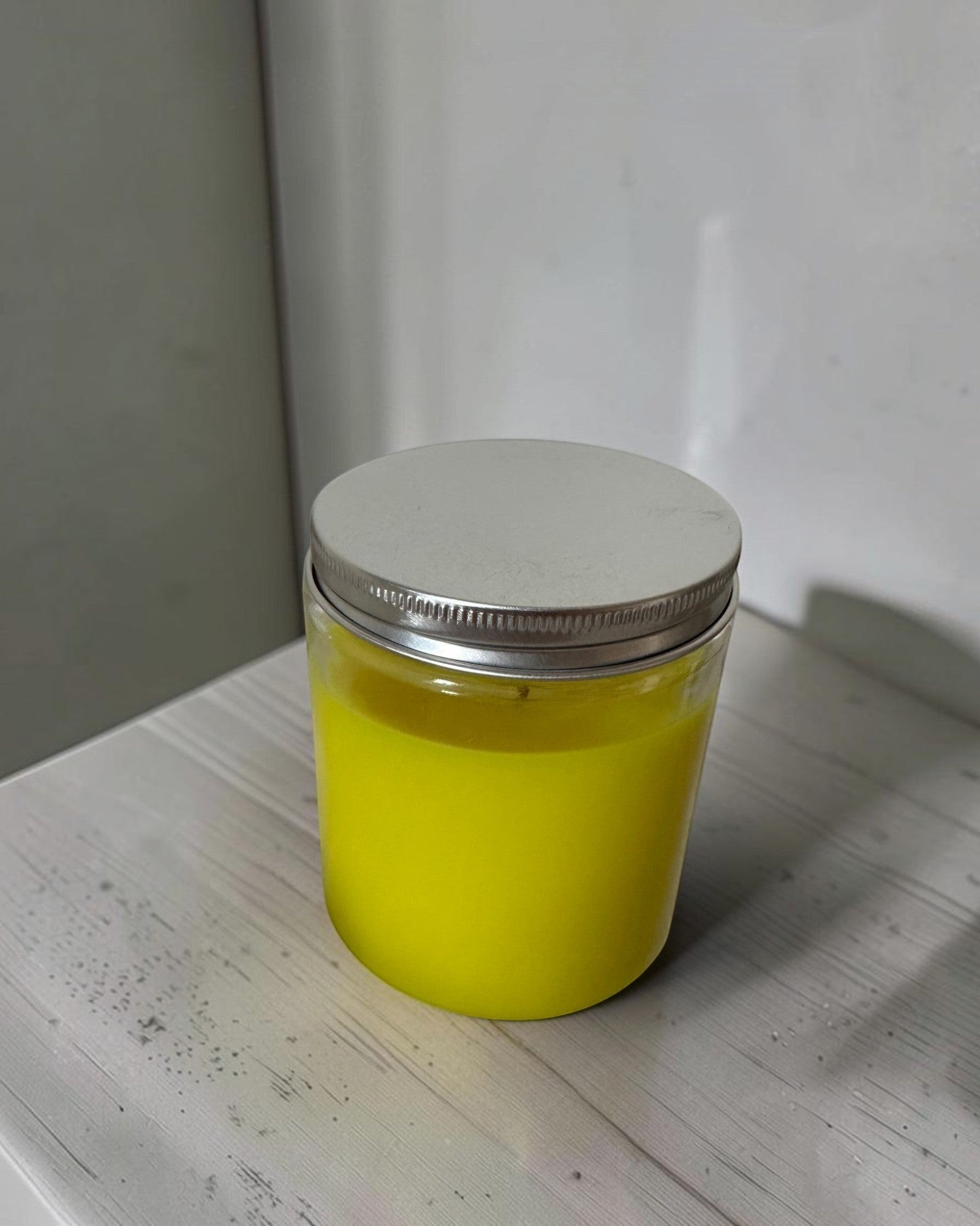 ELAIOPHOS vibrant yellow scented candle in a clear glass jar with a silver lid, perfect for home decor and ambiance.