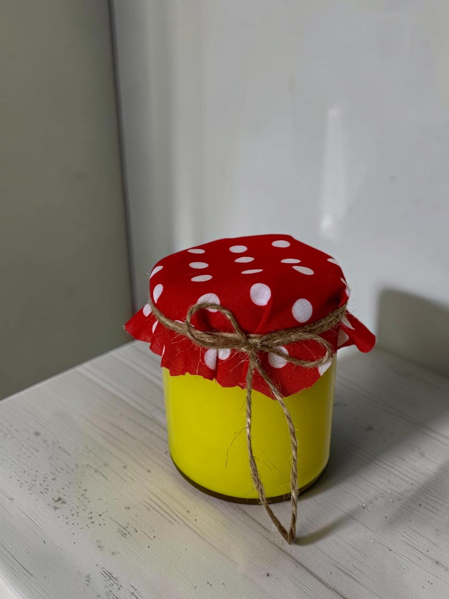 ELAIOPHOS yellow scented jar candle with red polka dot fabric lid tied with twine. Modern aesthetic, cozy ambiance.