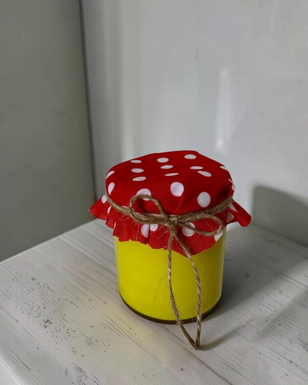 ELAIOPHOS yellow scented jar candle with red polka dot fabric lid tied with twine. Modern aesthetic, cozy ambiance.